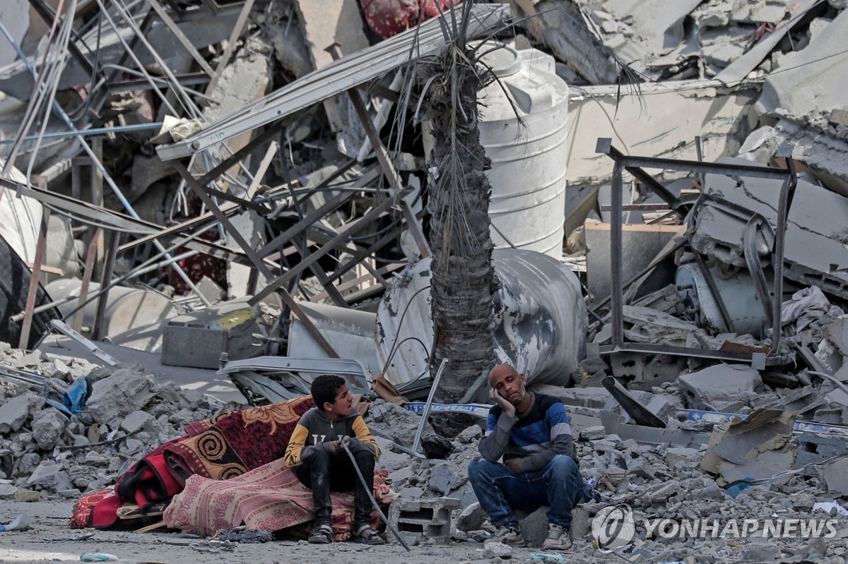 폐허된 거리에 앉아있는 팔레스타인 난민들
